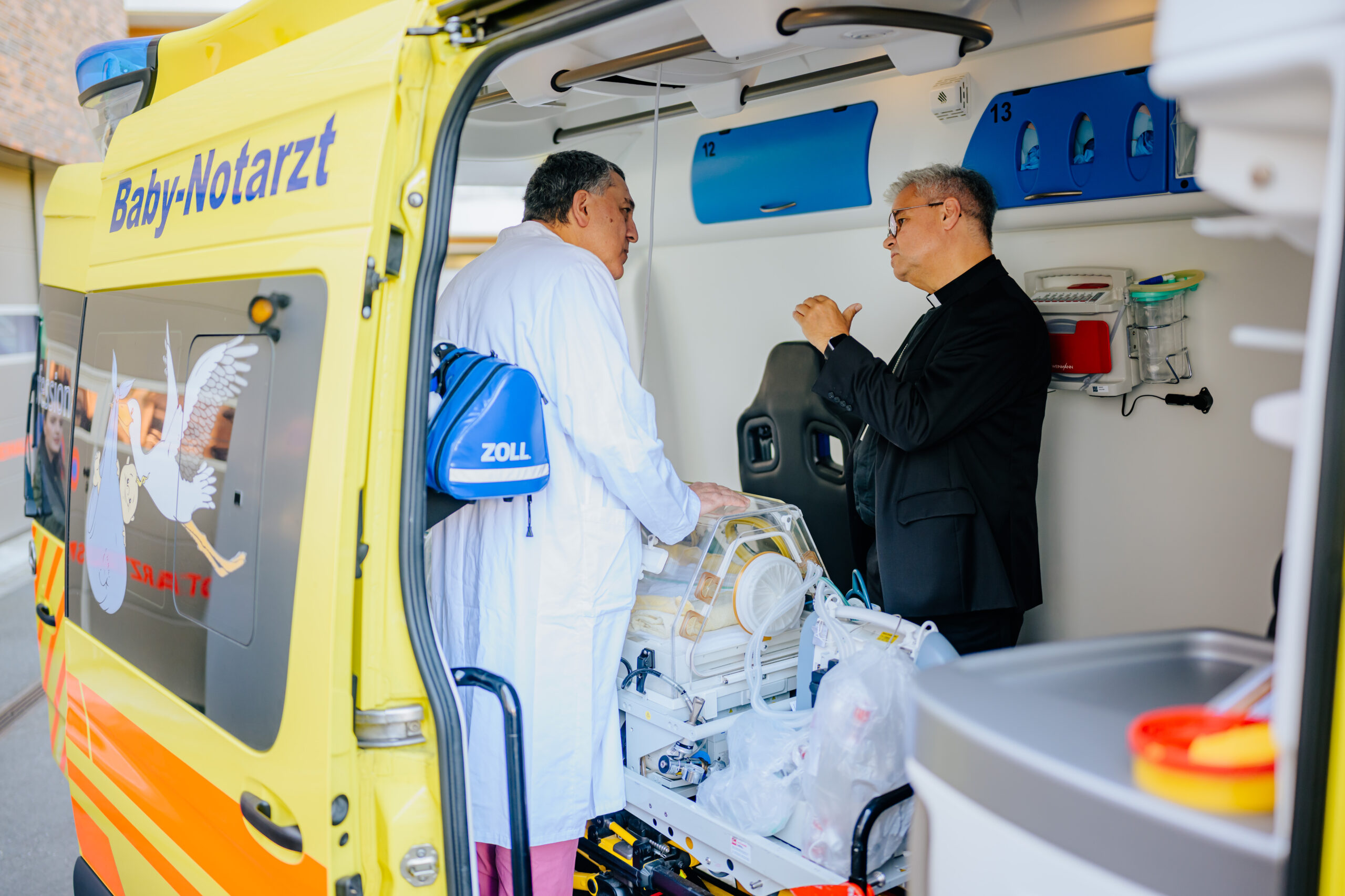 Dr. Bahman Gharavi, Chefarzt der Kinder- und Jugendklinik des Marien Hospital Witten, zeigt Erzbischof Dr. Udo Markus Bentz den Wagen des Projekts Baby-Notarzt.